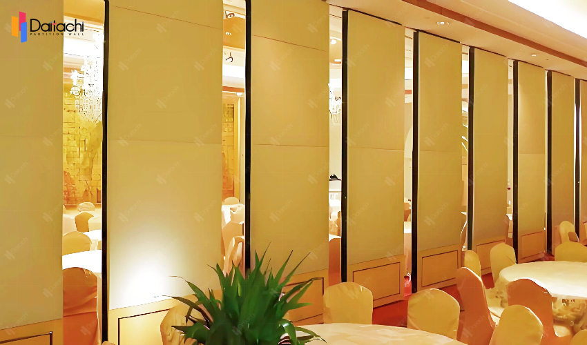 A simple, beige, manually movable partition wall in a dining area under yellow ambient lighting. A simple, beige, manually movable partition wall in a dining area under yellow ambient lighting.