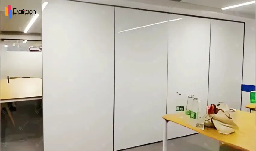 The classroom features a simple, off-white, manually movable partition wall.