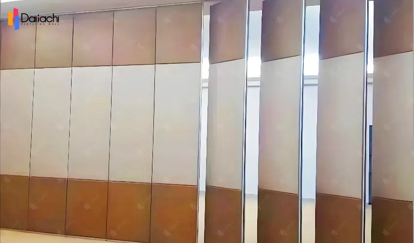 A manually operated movable partition wall with brown sections at the top and bottom and a white section in the middle. A manually operated movable partition wall with brown sections at the top and bottom and a white section in the middle.