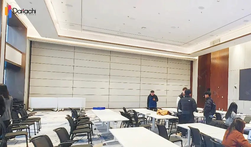 A pure white, minimalist, vertical lifting and folding wall inside a university classroom. A pure white, minimalist, vertical lifting and folding wall inside a university classroom.