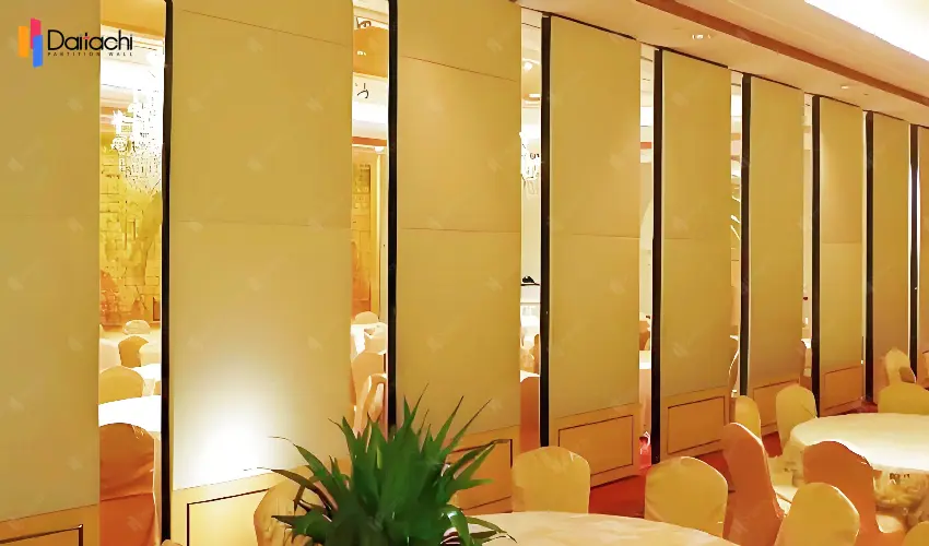 A simple, beige, manually movable partition wall in a dining area under yellow ambient lighting.